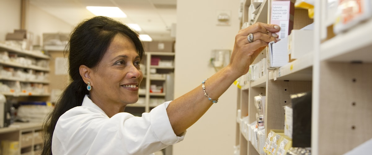 Pharmacist preparing prescription medicines at the dispensary shelves of Castlenau Pharmacy, London SW13